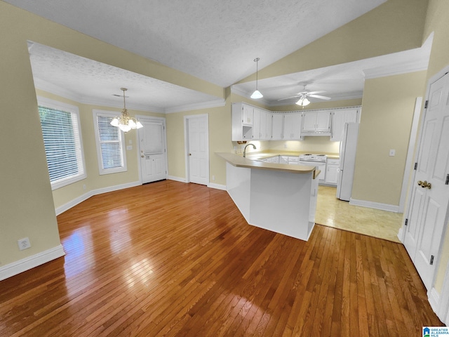 kitchen featuring kitchen peninsula, hardwood / wood-style floors, white cabinets, lofted ceiling, and white appliances