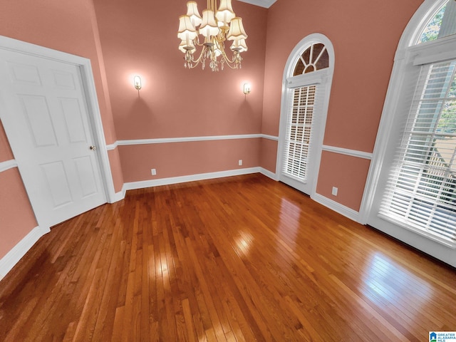 unfurnished room with hardwood / wood-style floors and an inviting chandelier