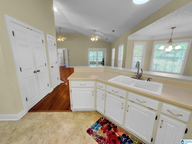 kitchen featuring lofted ceiling, hanging light fixtures, white cabinetry, light hardwood / wood-style floors, and sink