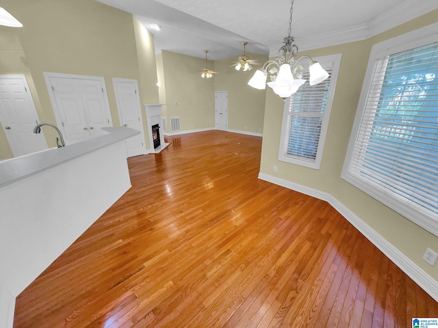 interior space featuring sink, crown molding, wood-type flooring, and ceiling fan with notable chandelier