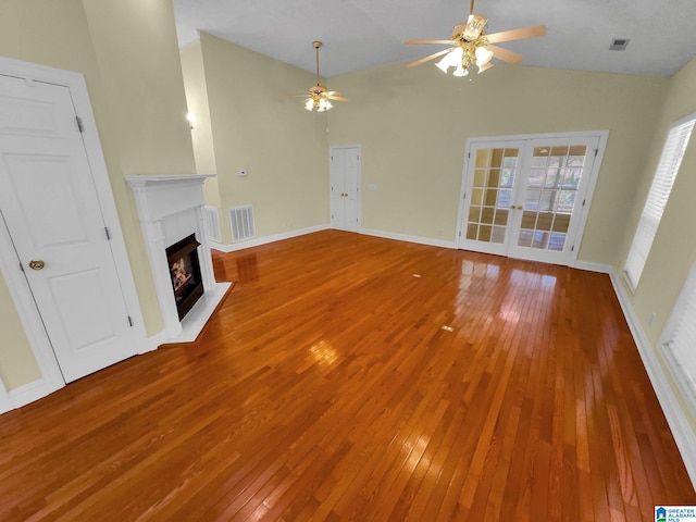 unfurnished living room with french doors, hardwood / wood-style flooring, vaulted ceiling, and ceiling fan