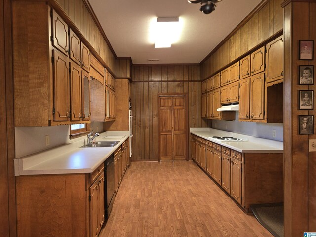 kitchen with light wood-style floors, light countertops, a sink, dishwasher, and wood walls