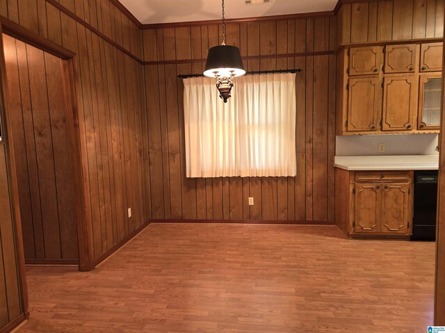 unfurnished dining area featuring light wood-style flooring, wooden walls, and baseboards