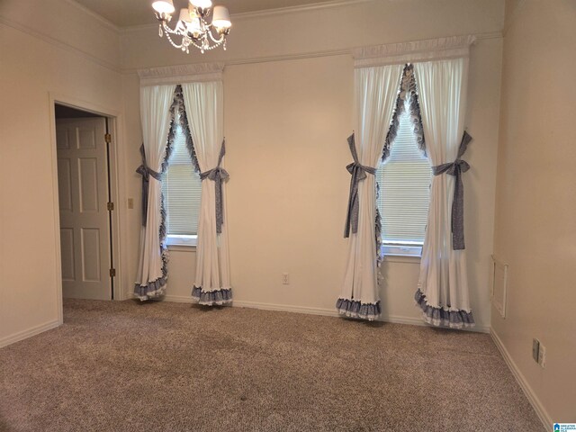 spare room featuring carpet flooring, a chandelier, baseboards, and ornamental molding