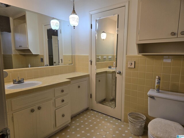 bathroom with vanity, toilet, and tile walls