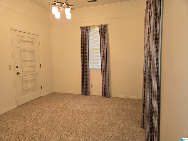 carpeted spare room with a chandelier, ornamental molding, and baseboards
