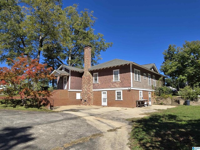 view of property exterior with a chimney and brick siding