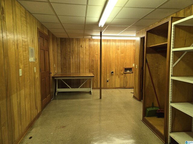 finished basement with tile patterned floors, wood walls, and a paneled ceiling