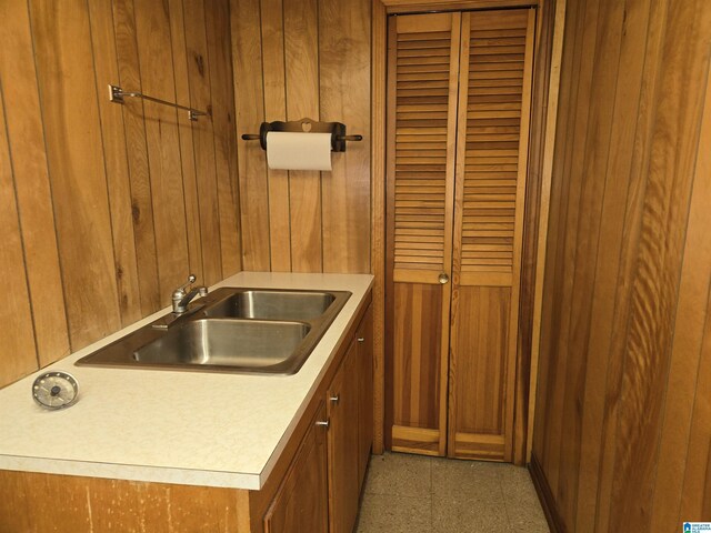 kitchen featuring a sink, wooden walls, brown cabinetry, and light countertops
