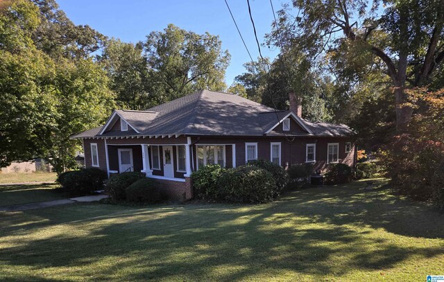 view of front of house with a front yard, a chimney, and roof with shingles