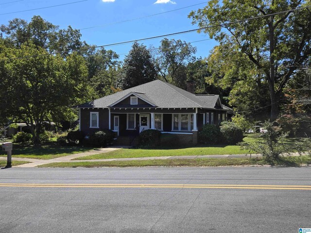 view of front of property with a front yard, covered porch, and a chimney