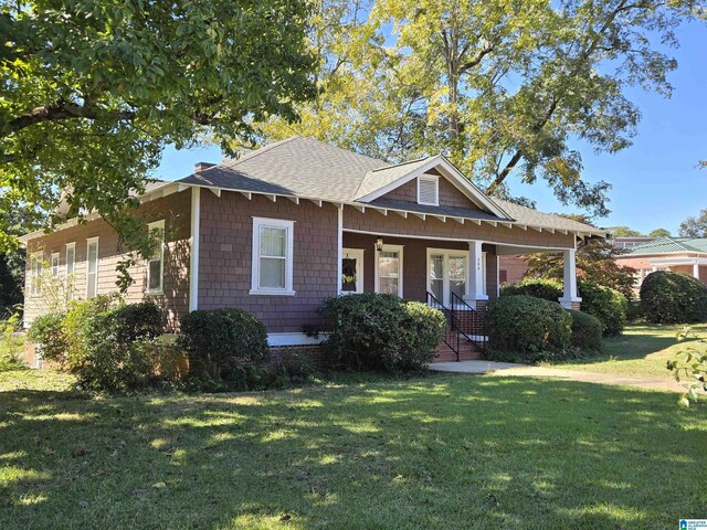 view of front of home with a front lawn, a porch, and a shingled roof
