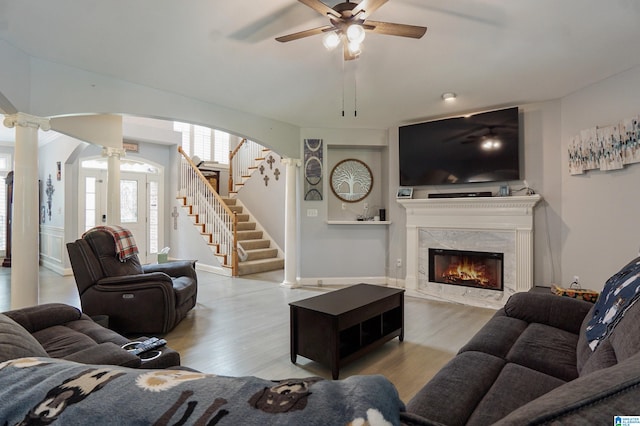 living room featuring light hardwood / wood-style floors, decorative columns, a fireplace, and ceiling fan