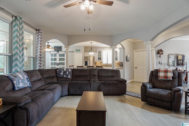 living room with light hardwood / wood-style flooring, crown molding, ornate columns, and ceiling fan