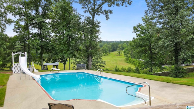 view of swimming pool with a patio area, a water slide, a yard, and a diving board