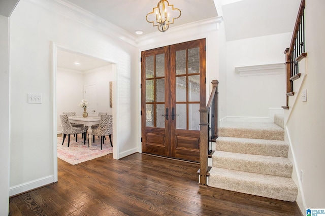 foyer entrance with an inviting chandelier, french doors, dark wood-type flooring, and crown molding