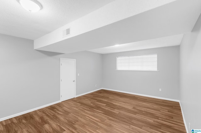 basement featuring hardwood / wood-style flooring and a textured ceiling