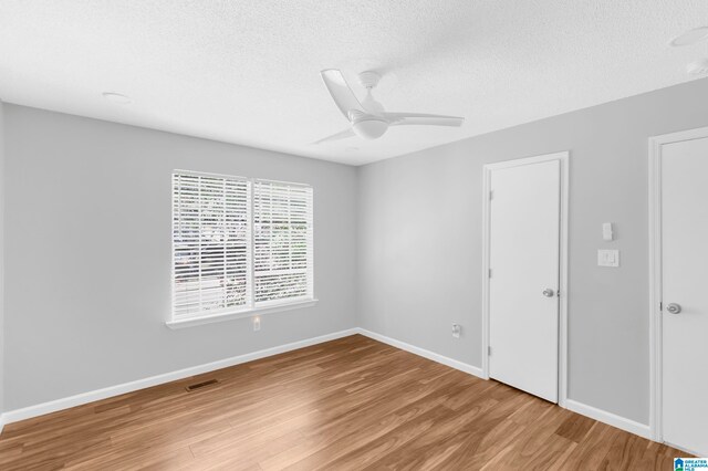 unfurnished room featuring light hardwood / wood-style floors, a textured ceiling, and ceiling fan