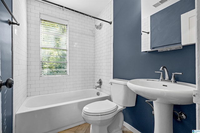 bathroom with toilet and tiled shower / bath