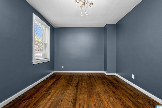 unfurnished room featuring a notable chandelier and dark hardwood / wood-style flooring