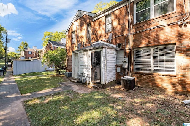 rear view of property with a lawn and central AC unit