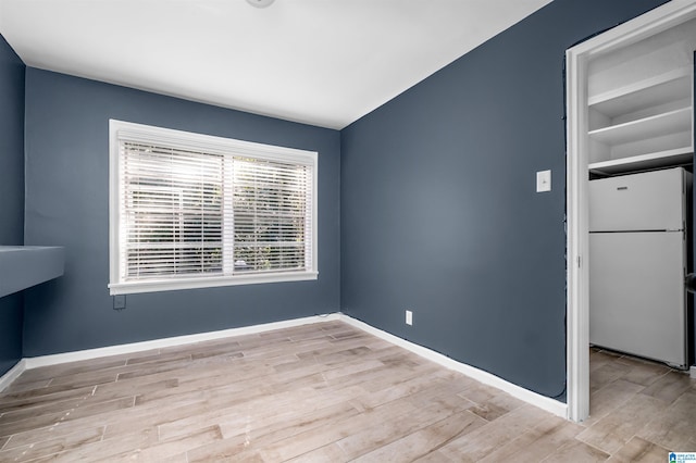 spare room with light hardwood / wood-style floors and built in shelves