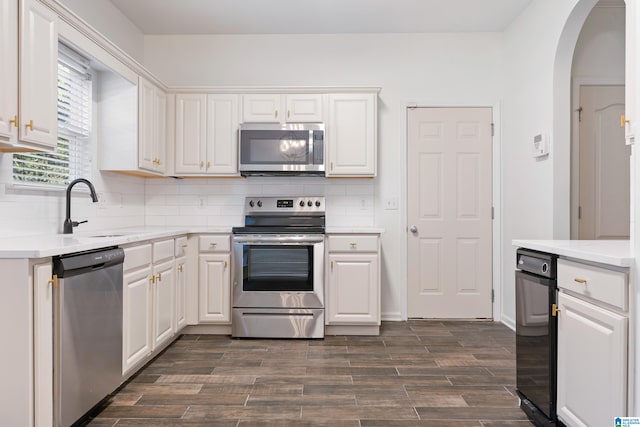 kitchen with appliances with stainless steel finishes, white cabinetry, sink, and dark hardwood / wood-style flooring