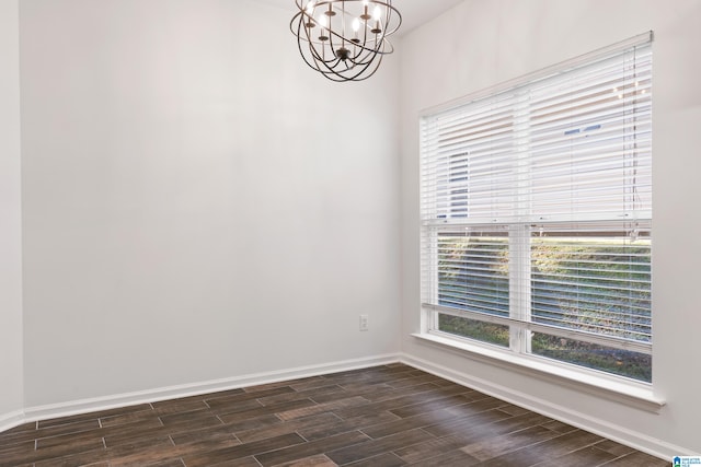 spare room with a chandelier and dark hardwood / wood-style flooring