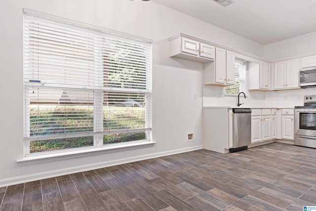 kitchen with white cabinets, stainless steel appliances, wood-type flooring, and backsplash