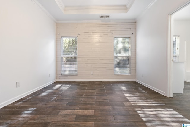 empty room with crown molding, a raised ceiling, and dark hardwood / wood-style flooring