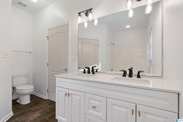 bathroom featuring toilet, walk in shower, hardwood / wood-style flooring, and vanity