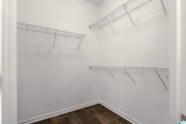 walk in closet with dark wood-type flooring