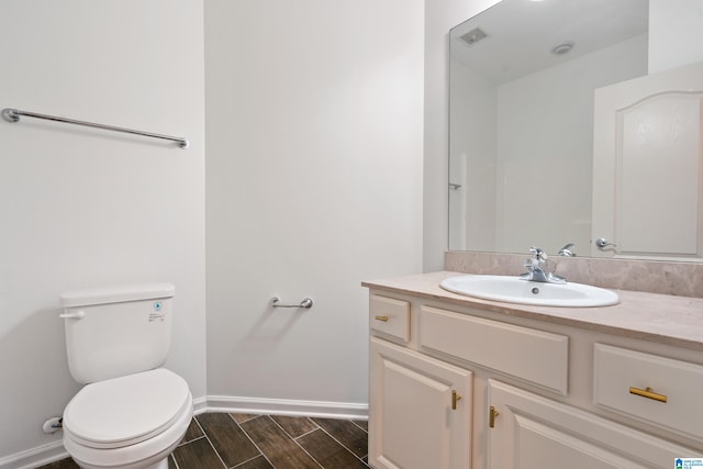 bathroom with vanity, toilet, and hardwood / wood-style flooring