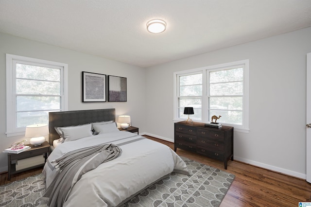 bedroom with multiple windows, dark hardwood / wood-style floors, and a textured ceiling