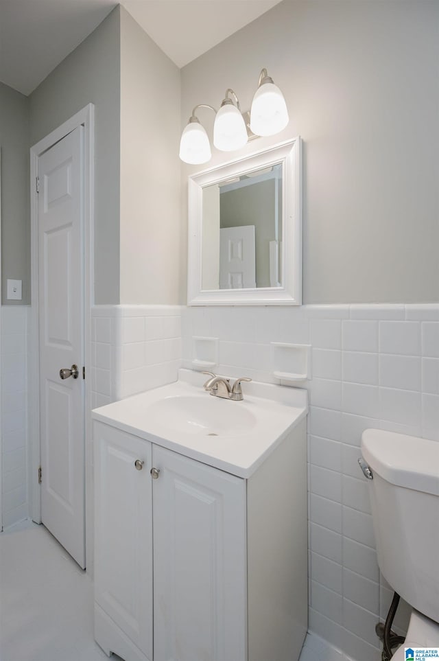 bathroom featuring vanity, toilet, and tile walls