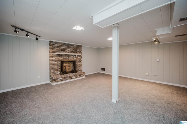 basement featuring crown molding, carpet flooring, rail lighting, and wooden walls