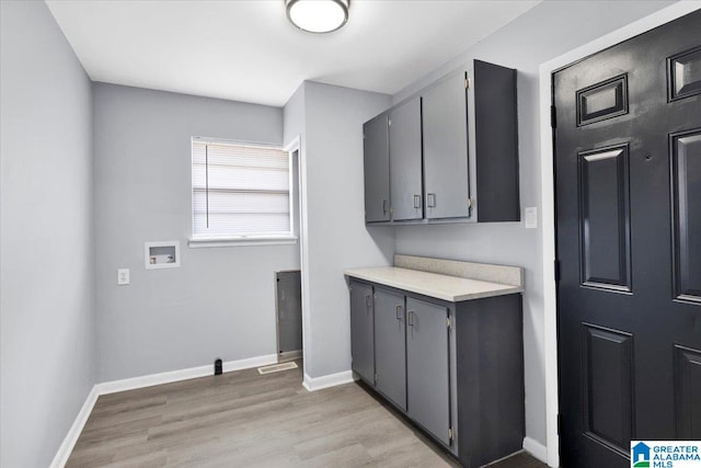 washroom with washer hookup, light hardwood / wood-style flooring, and cabinets