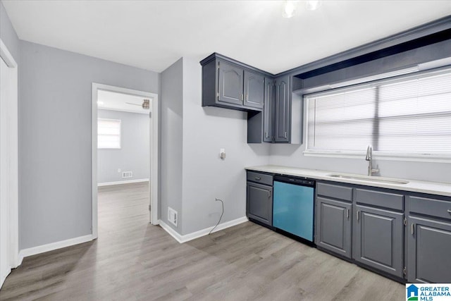 kitchen with stainless steel dishwasher, light hardwood / wood-style flooring, sink, and gray cabinetry