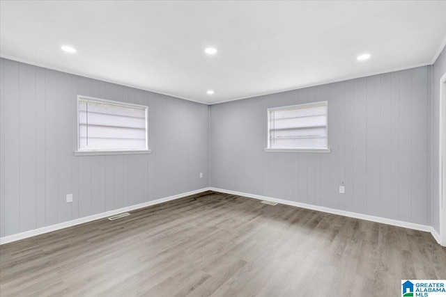 unfurnished room with a wealth of natural light, wood-type flooring, and wood walls