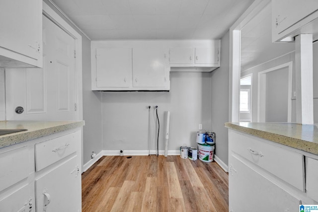 washroom with light hardwood / wood-style flooring, hookup for a washing machine, and cabinets