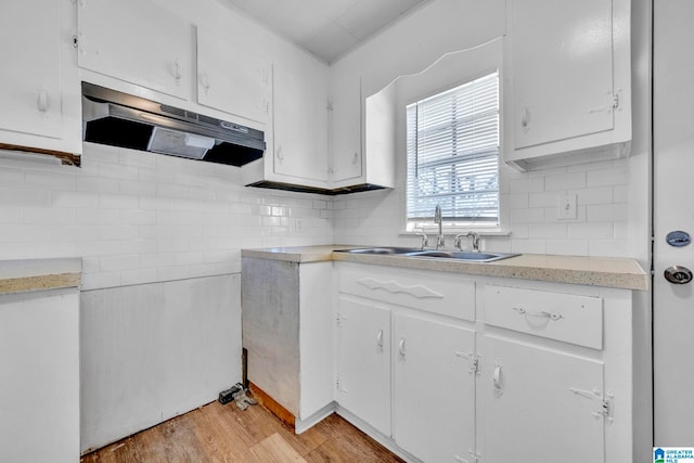 kitchen featuring decorative backsplash, sink, ventilation hood, light wood-type flooring, and white cabinets