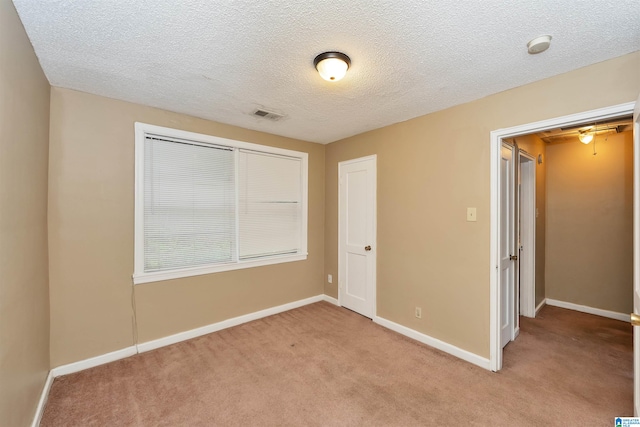 unfurnished bedroom featuring a closet, a textured ceiling, and light colored carpet