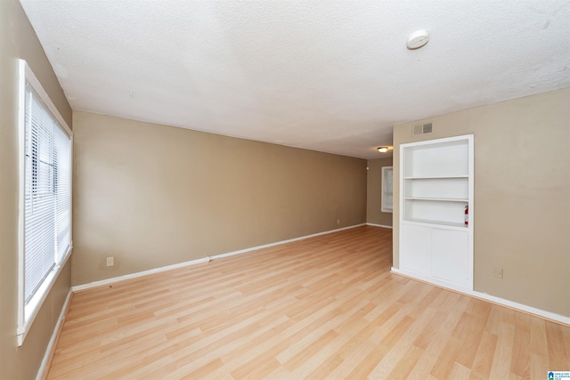 empty room with a textured ceiling and light wood-type flooring