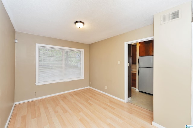 spare room featuring a textured ceiling and light wood-type flooring