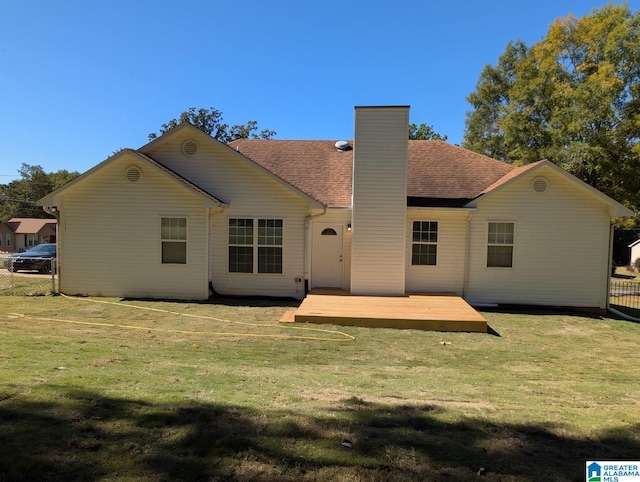 back of property with a wooden deck and a lawn