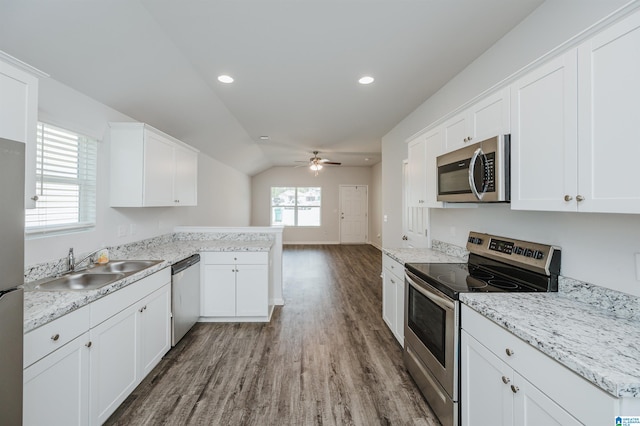 kitchen featuring kitchen peninsula, white cabinets, hardwood / wood-style flooring, vaulted ceiling, and stainless steel appliances