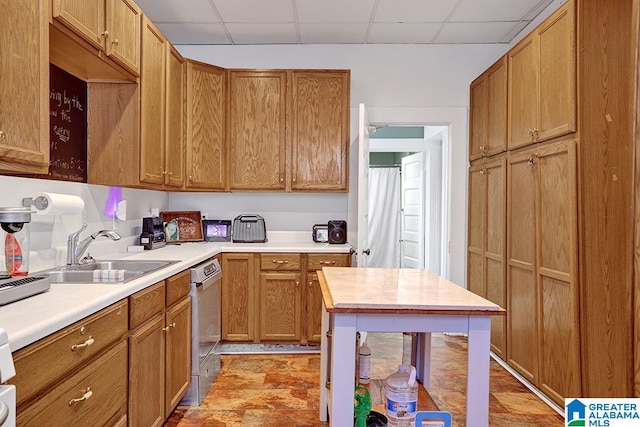 kitchen with stainless steel dishwasher, sink, and a drop ceiling