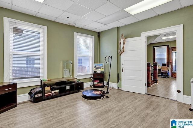 living area with a paneled ceiling and light hardwood / wood-style flooring