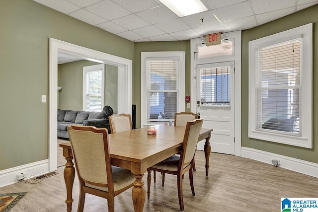 dining space featuring light hardwood / wood-style flooring and a paneled ceiling