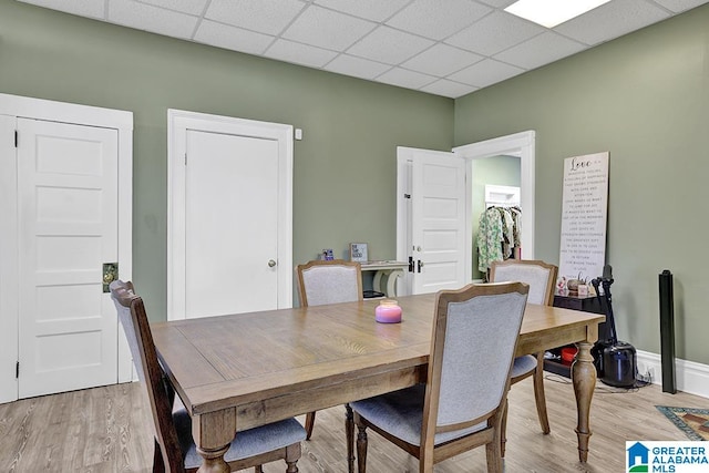 dining space with light hardwood / wood-style floors and a drop ceiling